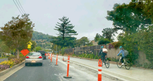 Cyclists on a raised path next to passenger cars