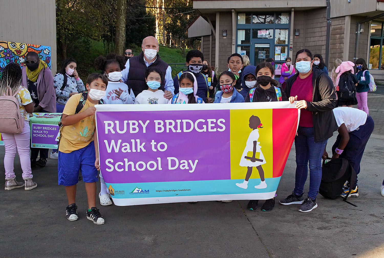 Students and teachers hold a banner: Ruby Bridges Wall to School Day